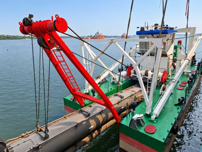 AI-enhanced company-supplied photo: Suction-pipe assembly and red lifting gantry along a dredger deck